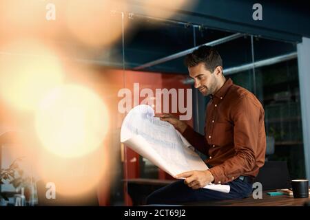 Architect reading blueprints while working late in his office Stock Photo