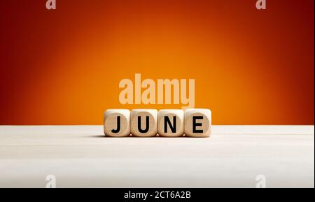 The month June written on wooden cubes with summer background with copy space. Month of the year. Stock Photo