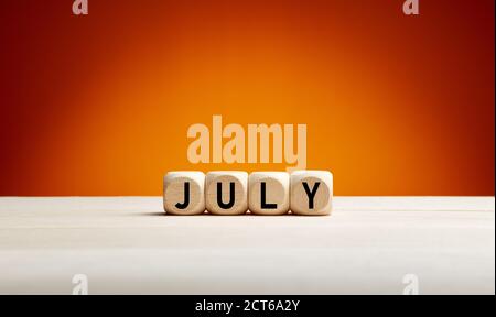 The month July written on wooden cubes with summer background with copy space. Month of the year. Stock Photo