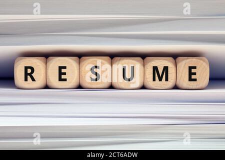 The word resume on wooden blocks against paper files and folders background. Job search and interview recruitment application concept Stock Photo