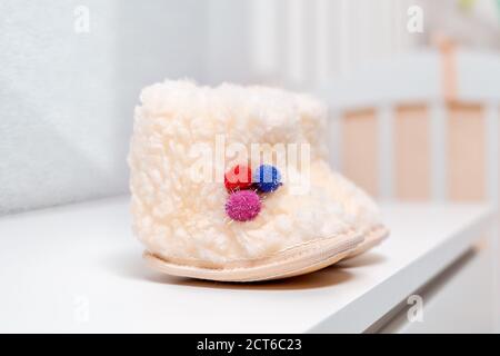 A pair of white wool baby booties are on the dresser. Close up. Nobody. Stock Photo