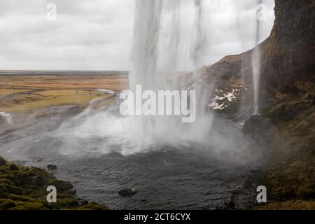 View from behind Seljalandsfoss waterfall on an overcast day, South Region, Iceland Stock Photo