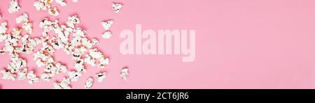 Popcorn scattered on pink background, top view. Stock Photo