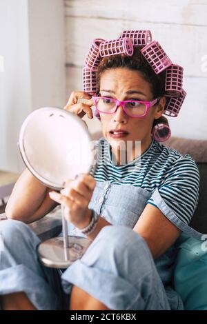 Adult pretty caucasian woman checking wrinkled near eye - concept of aging and time - blepharoplasty and eyelid surgery - people at home with mirror a Stock Photo