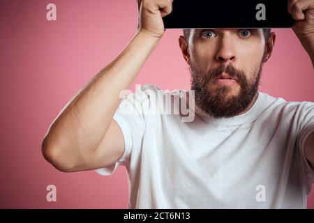 Man advertises a tablet on a pink background codes Space cropped view of emotions white t-shirt model new technologies Stock Photo