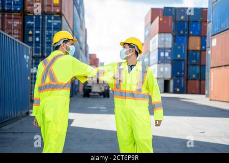 Foreman and dock worker staff are shaking elbows greeting each other at cargo container,Corona virus epidemic,Elbow greeting style. Stock Photo