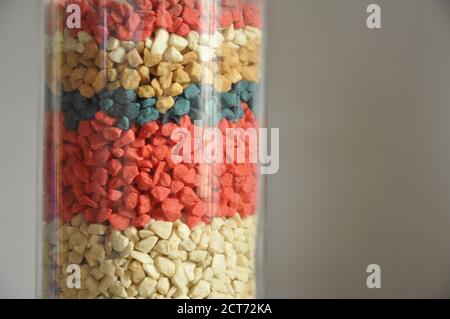 Glass vase, with an arrangement of colored or multicolored handmade stones, in various colors and layers photographed in zoom with copy space Stock Photo