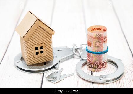 House, keys, money and handcuffs on the table. Fraud in the housing market Stock Photo