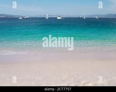 Turquoise sea and white sandy Rodas beach at the Cies islands, Galicia, Spain. Crystal clear shallow water and boats. Stock Photo