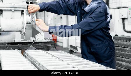 Working engineer performs work on setting up industrial repairs of equipment in production of bread Stock Photo