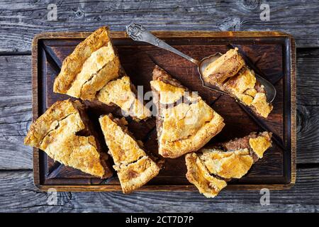 Classic american autumn dessert: apple pie with cinnamon and demerara sugar served on a dark rustic wooden background, top view, close-up Stock Photo