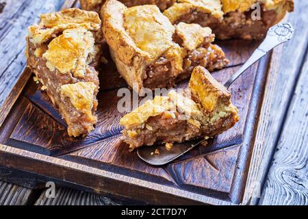 Classic american autumn dessert: apple pie with cinnamon and demerara sugar served on a dark rustic wooden background, top view, close-up Stock Photo
