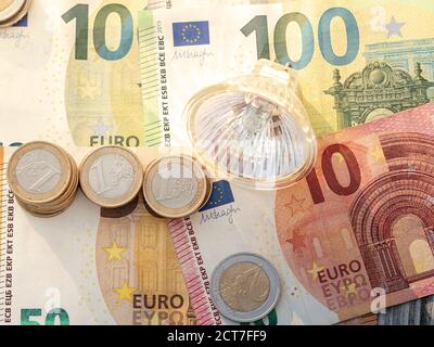 LED light bulb on euro coins and euro bills. Concept for electricity bill or savings from power supply change Stock Photo