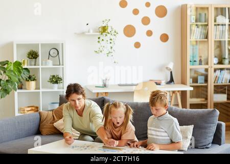 Wide angle portrait of loving family with special needs child playing with puzzles and board games together at home, copy space Stock Photo