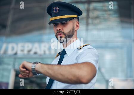 Handsome male pilot looking at wristwatch on the street Stock Photo