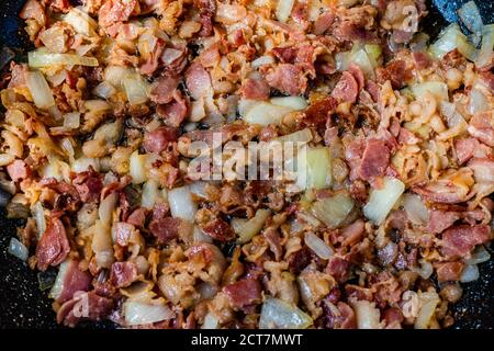 Fried bacon with onions in the frying pan Stock Photo