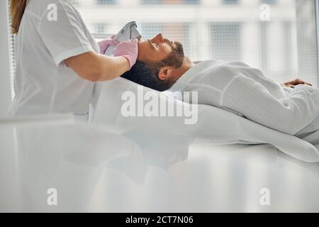 Female cosmetologist treating male face skin with laser device Stock Photo
