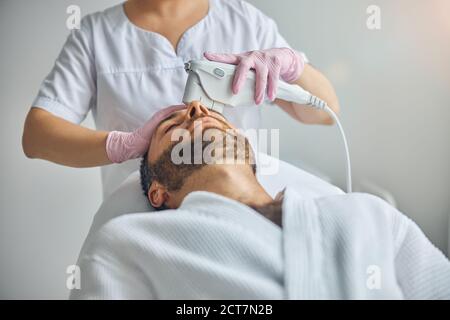 Female beautician treating male skin with laser device Stock Photo