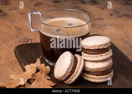 Cup of coffee and chocolate macarons on wooden background. Cozy autumn composition - Image Stock Photo