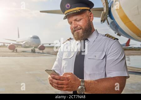 Positive pilot using his modern gadget outdoors Stock Photo