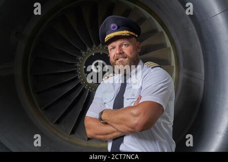 Gladsome bearded airman near the turbine of his plane Stock Photo