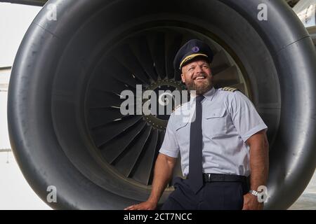 Happy optimistic pilot posing on the plane turbine Stock Photo