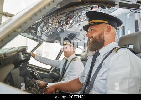 Contented experienced men navigating the aircraft and smiling Stock Photo