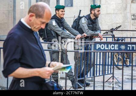 Priest looks at the map and police officers on duty near Damascus Gate at the old city of Jerusalem. They were built in 16th century and are a typical Stock Photo