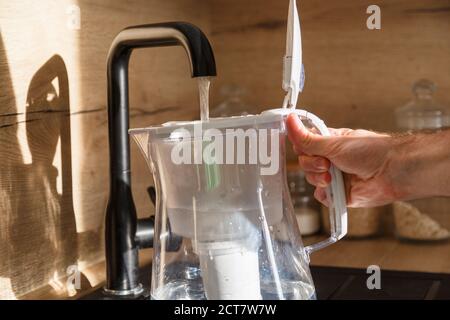 Water filter jug in kitchen sink, filling up. Stock Photo