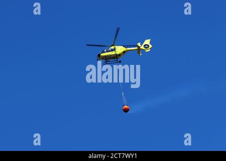 Firefighting helicopter carry water bucket to extinguish the fire or forest fire.  Stock Photo