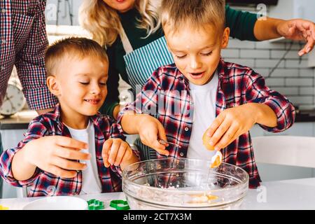 Happy family of mother, father and two children twins sons bake cookies in kitchen before Christmas Stock Photo