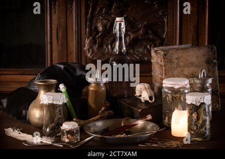 eerie witches' kitchen with lot of ingredients for a potion and ancient gruesome jars dark with only candlelight for Halloween Stock Photo