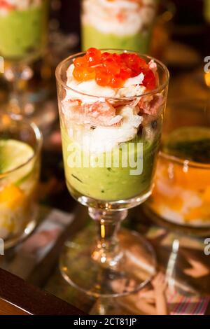 Verrine with avocado cream, shrimp, salmon eggs in an old sculpted glass. Stock Photo