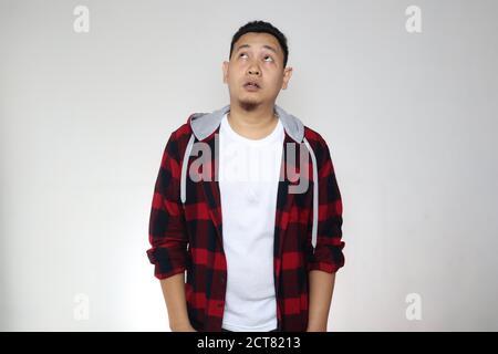 Funny young confused Asian man thinking expression, looking up contemplation gesture over white background Stock Photo