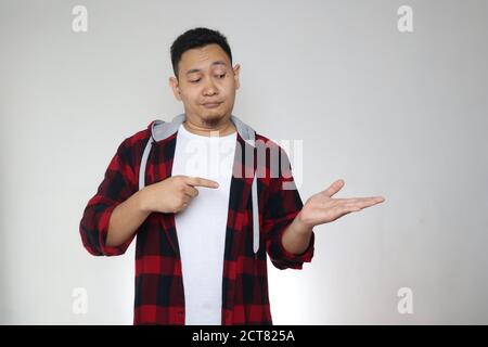 Young Asian man showing something on empty hand, smiling expression. Close up body portrait Stock Photo