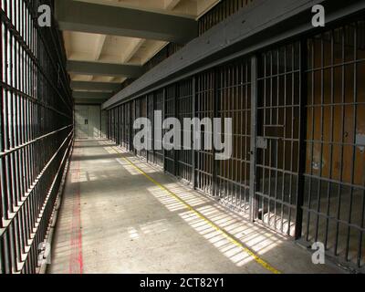 View of iron bars inside closed jail cell block in an unused rundown government owned facility. Stock Photo
