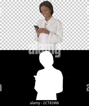 Smiling African American female doctor texting message on smartp Stock Photo