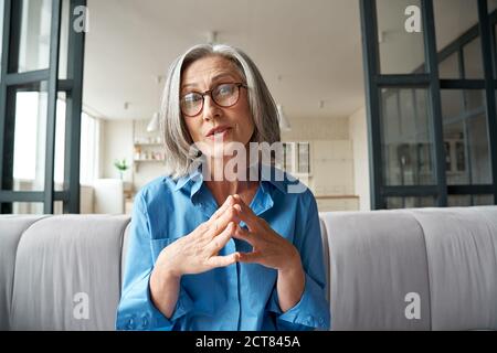 Mature woman online teacher distance therapist looking at web cam video calling. Stock Photo