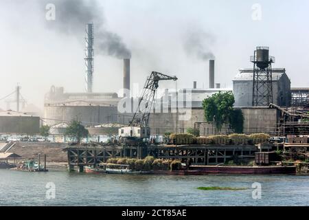 LUXOR, EGYPT - MARCH 16, 2010 : Smoke billows from the chimneys stacks of factories which line the bank of the River Nile south of Luxor in Egypt. In Stock Photo