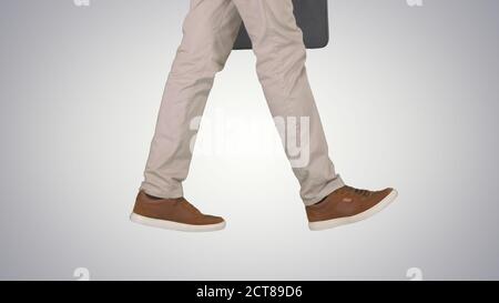 Mans feet is walking in jeans and sneakers on gradient backgroun Stock Photo