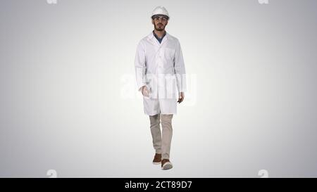 Young engineer in robe and helmet putting glasses on while walki Stock Photo