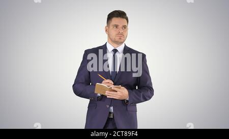 Handsome experienced manager writing in notebook his ideas while Stock Photo