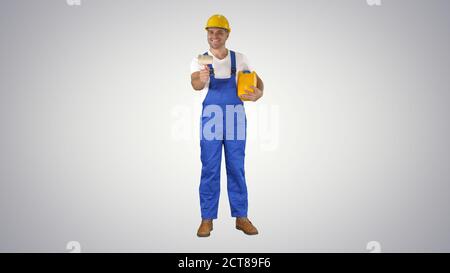 Worker holding paint brush smiling to camera on gradient backgro Stock Photo