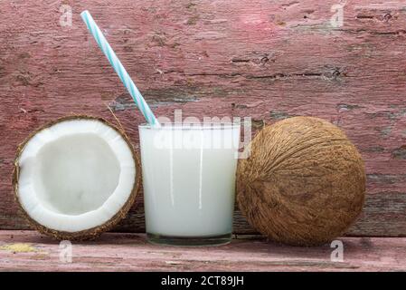 Glass of fresh coconut milk. Fruit cut in half and fresh. Coconut milk is extracted from the pulp of the coconut fruit, one of the main vegetable reso Stock Photo