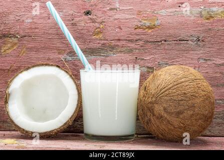 Glass of fresh coconut milk. Fruit cut in half and fresh. Coconut milk is extracted from the pulp of the coconut fruit, one of the main vegetable reso Stock Photo