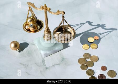 Cost of Christmas holidays concept. Weight scales, vintage balance with stack of coins and Xmas golden trinkets. Stock Photo