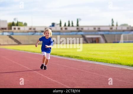 Child running in stadium. Kids run on outdoor track. Healthy sport activity for children. Little boy at athletics competition race. Young athlete in t Stock Photo