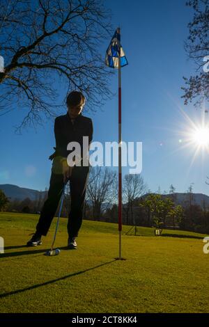Golfer on the Putting Green with Sunlight. Stock Photo