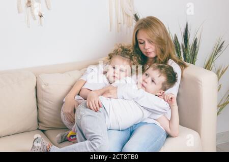 Mom hugs her kids while resting on the couch. Stock Photo