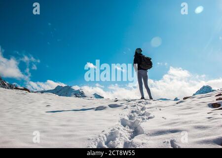 A young woman on a snow top amid a blue sky. White clouds. Stock Photo